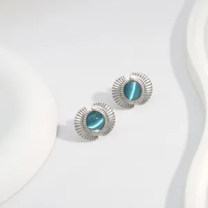 Detail view of fan-shaped stud earrings with blue cat-eye stone in silver metal