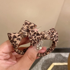 Detail view of two leopard print bow hair ties made of soft fabric on a hand