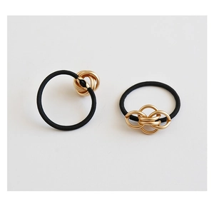 Close-up of two black elastic hair ties with elegant golden interlocking metal ring detail