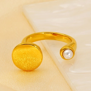 Close-up of gold plated ring with brushed metal disk and white pearl detail