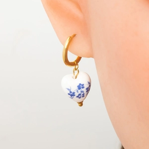 Golden hoop earrings with heart-shaped blue and white floral porcelain charms