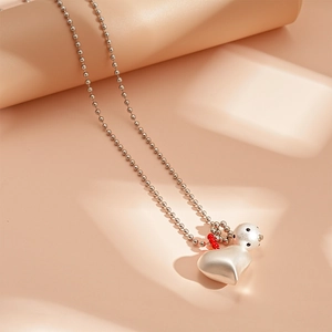Detail of silver bead chain necklace featuring a matte heart pendant and a bear charm