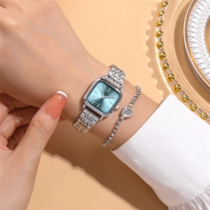 Close-up of square silver watch with turquoise dial and heart crystal bracelet on wrist