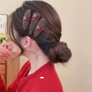 Detailed close-up of brown plush hair clips with red cherry and gold bow decorations