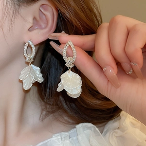 Detail of floral drop earrings with white petals and sparkling crystals on model