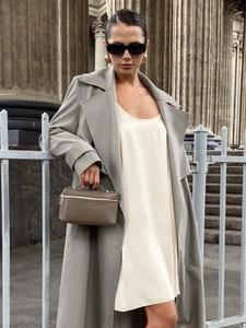 Detail of satin slip dress paired with trench coat and leather handbag outfit
