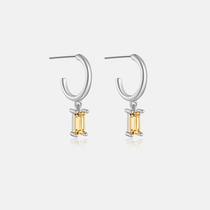 Macro detail of S925 silver hoop earrings featuring a rectangular yellow gemstone