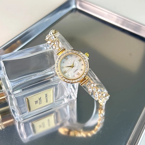 Detailed macro shot of a gold leaf bracelet watch with crystal bezel and mother of pearl dial