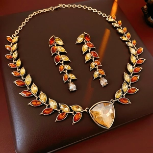 Détail d'une parure vintage feuille dorée avec strass orange et ambre éclatants