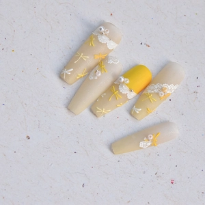 Details von matten gelben Press-on Nails mit Libellendesign und Spitzenstruktur