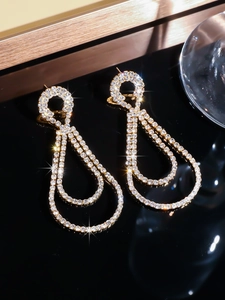 Macro detail of luxury gold-plated drop earrings with sparkling pavé rhinestones