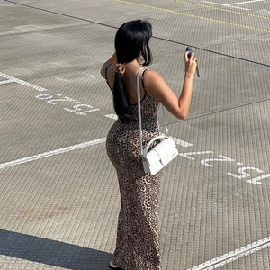 Outdoor back view of a slim leopard print maxi dress paired with a white handbag