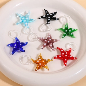 Detailed view of colorful 3D glass starfish pendants with white polka dots in a white bowl
