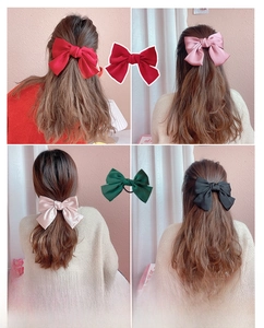Close-up of oversized satin bow hair clips in red, pink, champagne and green colors
