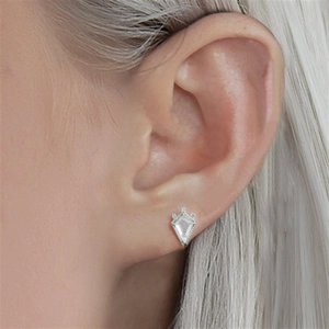 Close-up of a shield-shaped silver earring with clear gemstone on a model's ear