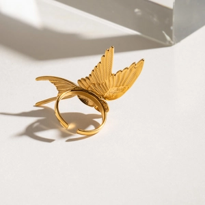 Detailed close-up of a golden bird-shaped open ring on a clean minimalist background