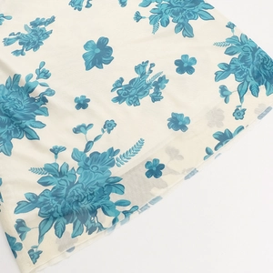 Detalle de estampado floral azul en tela de malla crema con costura de dobladillo