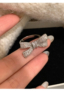 Detailed view of silver bow ring set with sparkling cubic zirconia on a finger
