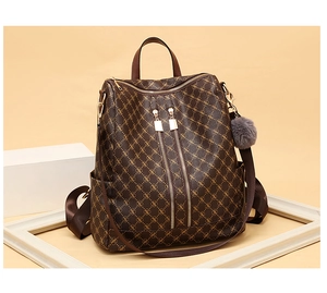 Detail view of brown vintage monogram backpack with golden zippers and plush ball charm