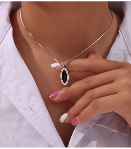 Detail of silver box chain necklace with black oval gemstone pendant worn by a model
