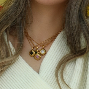 Close-up of a gold square zircon pendant with a vintage texture on a twisted chain