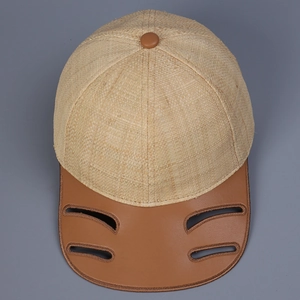 Top view of raffia baseball cap featuring brown leather brim with cutout details