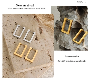 Macro shot of rectangular gold and silver geometric earrings on textured stone