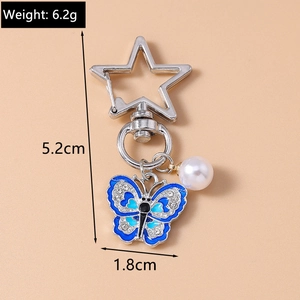 Detailed view of blue enamel butterfly keychain with pearl and size specifications
