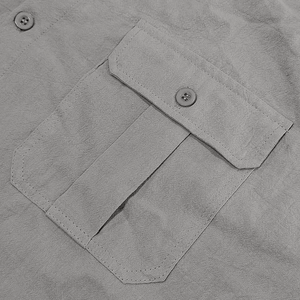 Detail shot of the grey linen shirt chest pocket with visible stitching and button
