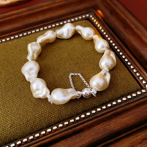 Macro detail of irregular baroque pearl bracelet with silver magnetic clasp on green velvet