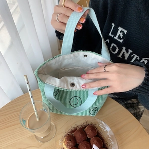 Detail of green corduroy tote bag with smiley face print and light blue handles