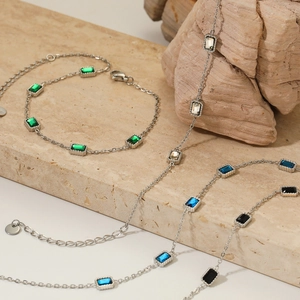 Dettaglio di bracciali a catena argento con pietre quadrate colorate su base di pietra