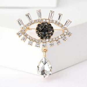 Detail of golden evil eye brooch with rhinestones and clear water drop crystal pendant