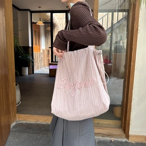 Close-up of pink corduroy tote bag with Bonjour embroidery and drawstring closure detail