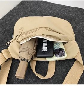 Top view of beige nylon crescent bag interior showing capacity for umbrella and phone