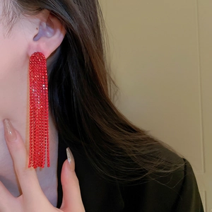 Detailed close-up of long red tassel earrings with sparkling rhinestones on model