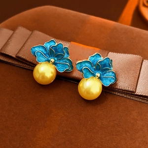 Macro detail of vintage blue flower earrings with gold petals and hanging pearl