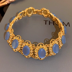 Close-up of vintage gold bracelet with oval blue gemstones and floral metal engravings