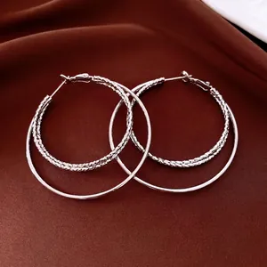 Boucles d'oreilles doubles anneaux argentés avec textures sur satin sombre