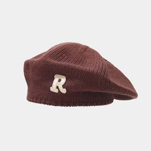 Close-up of thick knitted dark brown beret with white chenille R letter patch