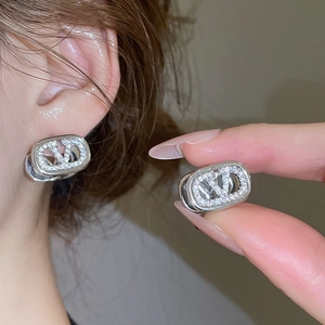 Macro detail of silver V-logo earrings with oval frame and pavé cubic zirconia