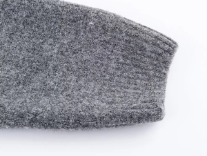 Close-up of grey plush knit cardigan sleeve with detailed ribbed cuff texture