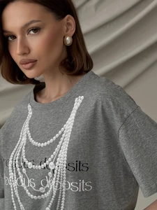 Detail of grey cotton T-shirt featuring pearl necklace print and precious deposits text