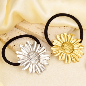 Close-up of gold and silver daisy flower charms on premium elastic hair ties on silk