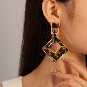 Close-up of geometric leopard print earrings with gold frames on a model's ear