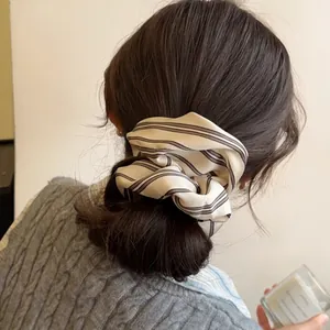 Minimalist striped scrunchie in beige chiffon with black stripes on a ponytail