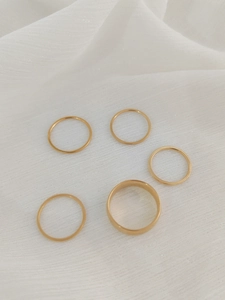 Detail of five stackable gold-plated rings including one wide band and four thin rings