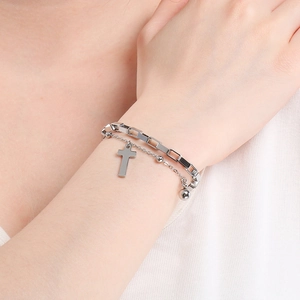 Close-up of double-layered silver cross bracelet with beads on female wrist