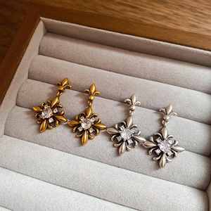 Close-up of gold and silver vintage zircon fleur-de-lis earrings on velvet display