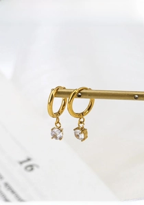 Macro shot of gold-plated titanium steel earrings with sparkling round zircon pendants